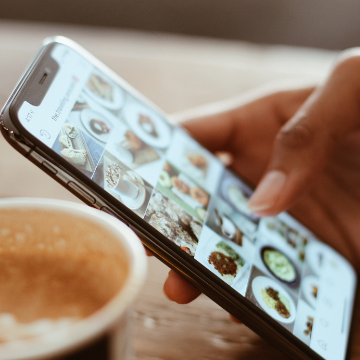 hand scrolling on phone with coffee